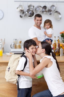 Attentive mother giving school lunch to her son in the kitchen