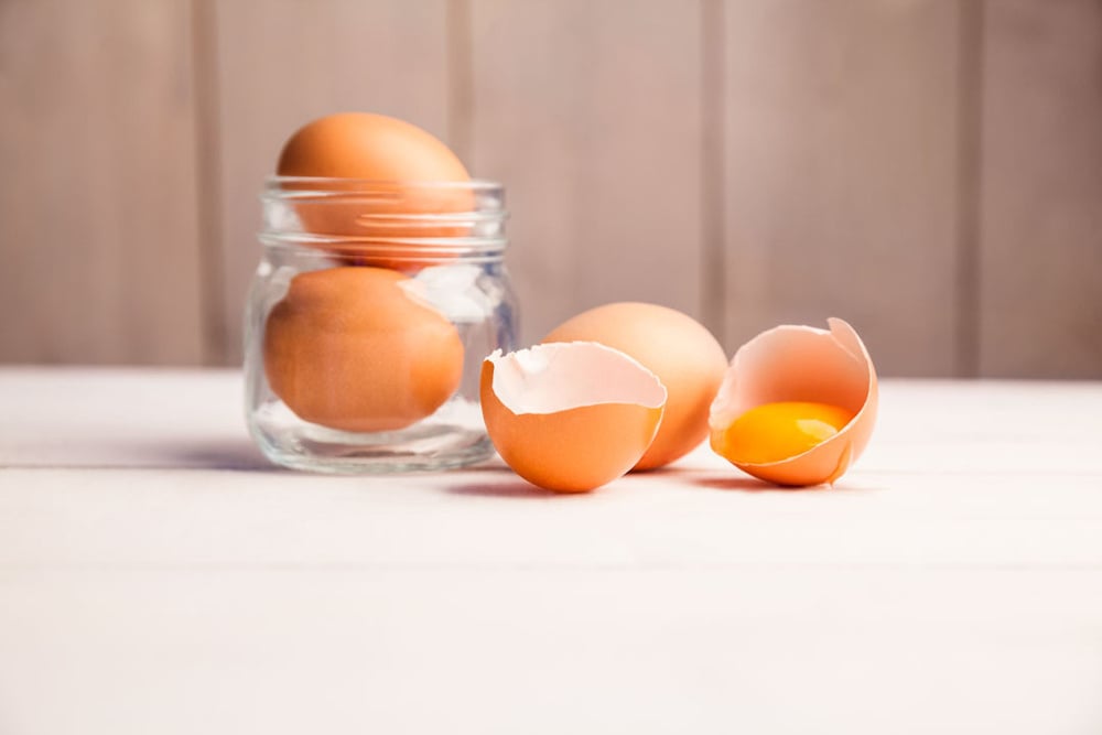 Eggs in a jar by broken egg shells on the table