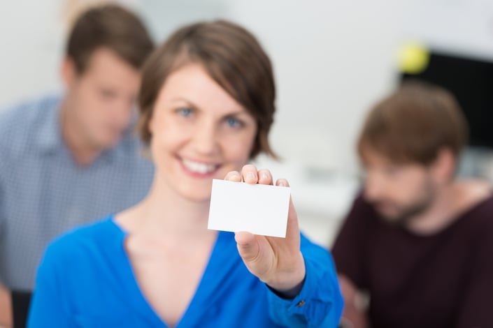 A businesswoman holds up a blank white card, standing in for a credential that shows only what a resume chooses to display