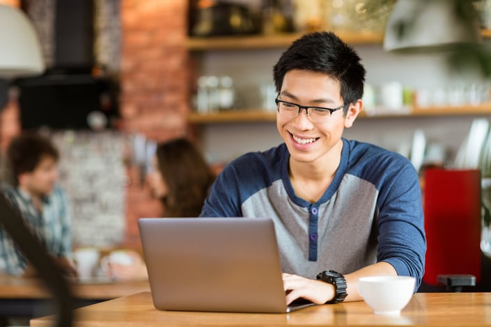 A young professional works on a laptop in a cafe, representing the concrete skills a person can demonstrate today