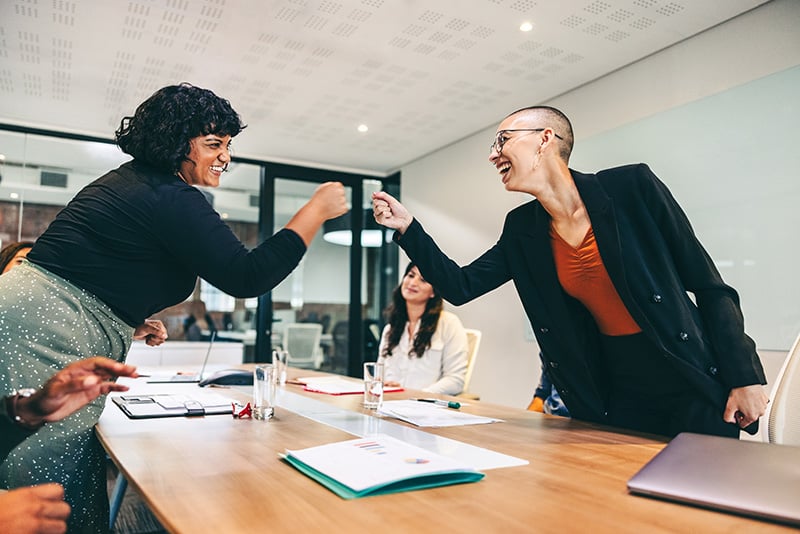 two business women fist umping