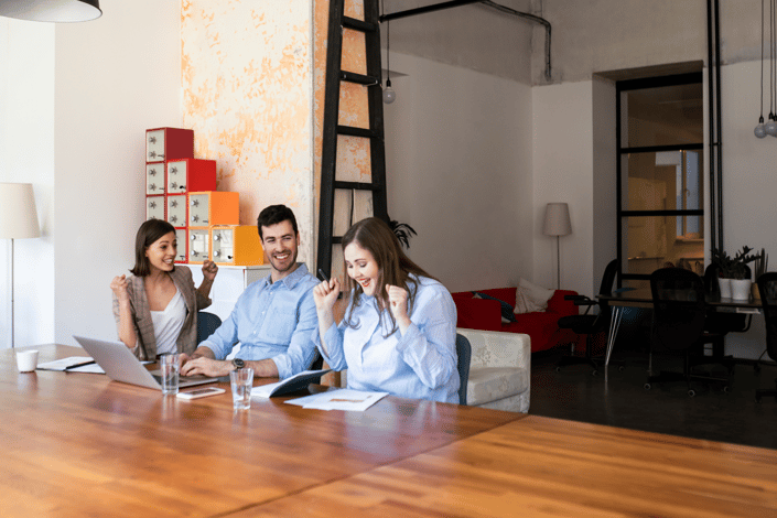 Three colleagues at a laptop share a small celebration, capturing the confidence of a team that has narrowed its provider search down to the right finalist