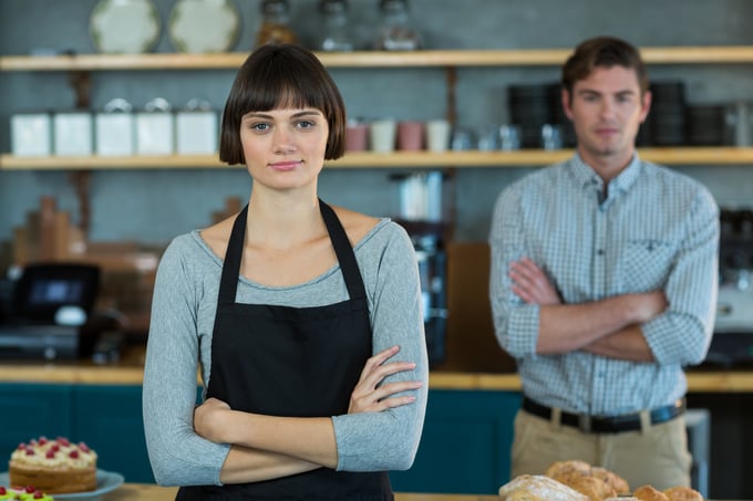 Portrait of waitress standing with arms crossed in cafe