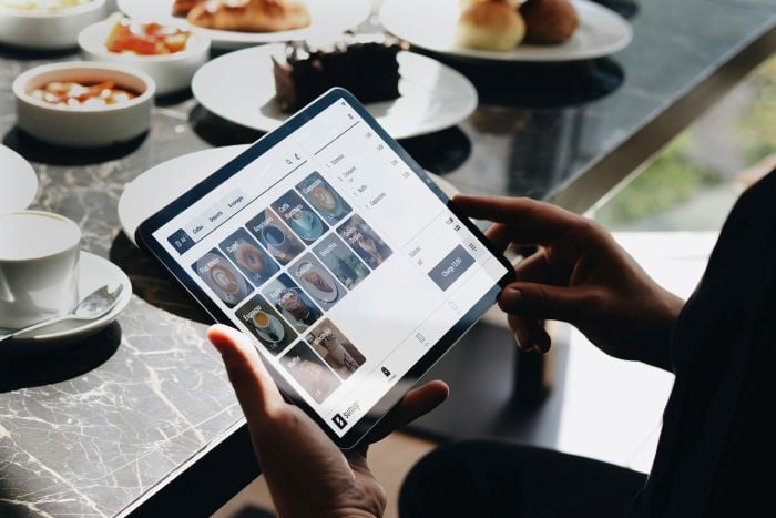 Restaurant Manager on Tablet with POS software and food on table