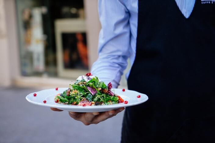A server carries plates through a busy restaurant dining room