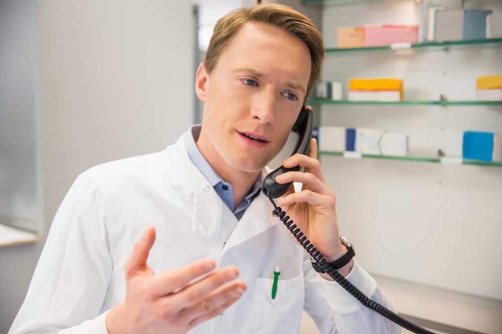 Serious pharmacist on the phone at the hospital pharmacy