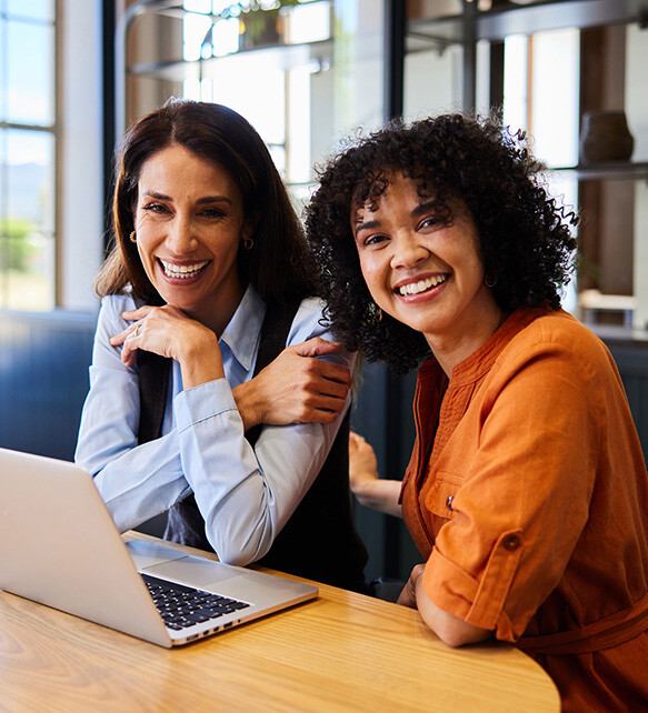 two women smiling in front of computer
