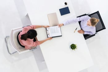 Woman handing another woman resume