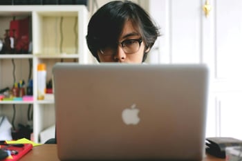 Young man wearing glasses using laptop
